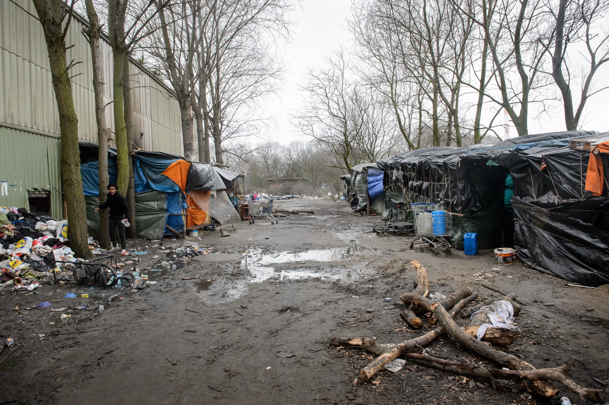 Calais, December 2014 View on part of the Tioxide jungle, a camp situated next to a chemical plant. The camp, initially not more than a small collection of shelters, has grown into the largest camp in Calais, housing more than 800 persons. With the construction of a makeshift church, mosque, barbershop and shop, life has gotten increasingly organized over the last months. But without any electricity or running water, living conditions are squalid.