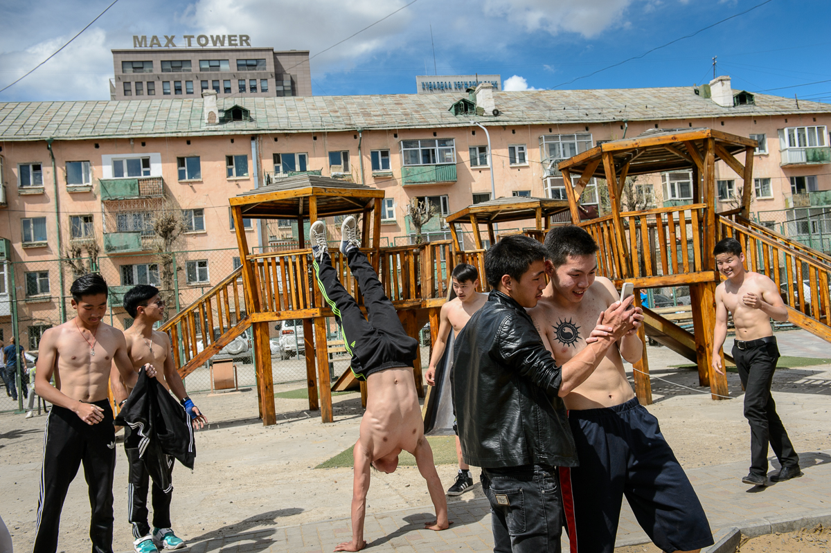 Teenage boys show off their gymnastic skills and tricks in a communal courtyard of Soviet-era buildings in the center of UB.