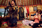 Standing next to his sleeping one-month old son, Otgonbold (27) dresses for a shamanistic ceremony while his wife Anudari (25), a dentist and a shaman as well, shows pictures to her friend Azza.  Although the couple live in an apartment in downtown UB, their shamanistic ceremonies are held in their ger, a round felt tent, set up on the outskirts of the city.