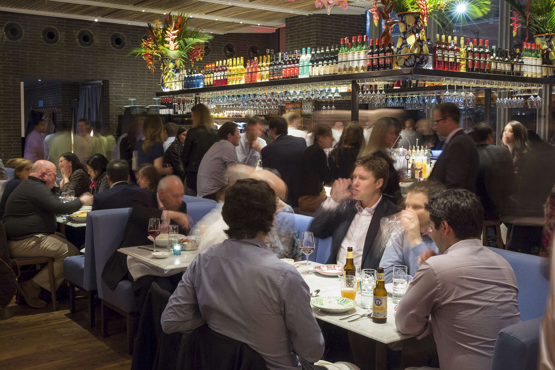 Diners in the main room at Santina restaurant in New York, NY. Additional guests eat and drink in the adjacent bar area.