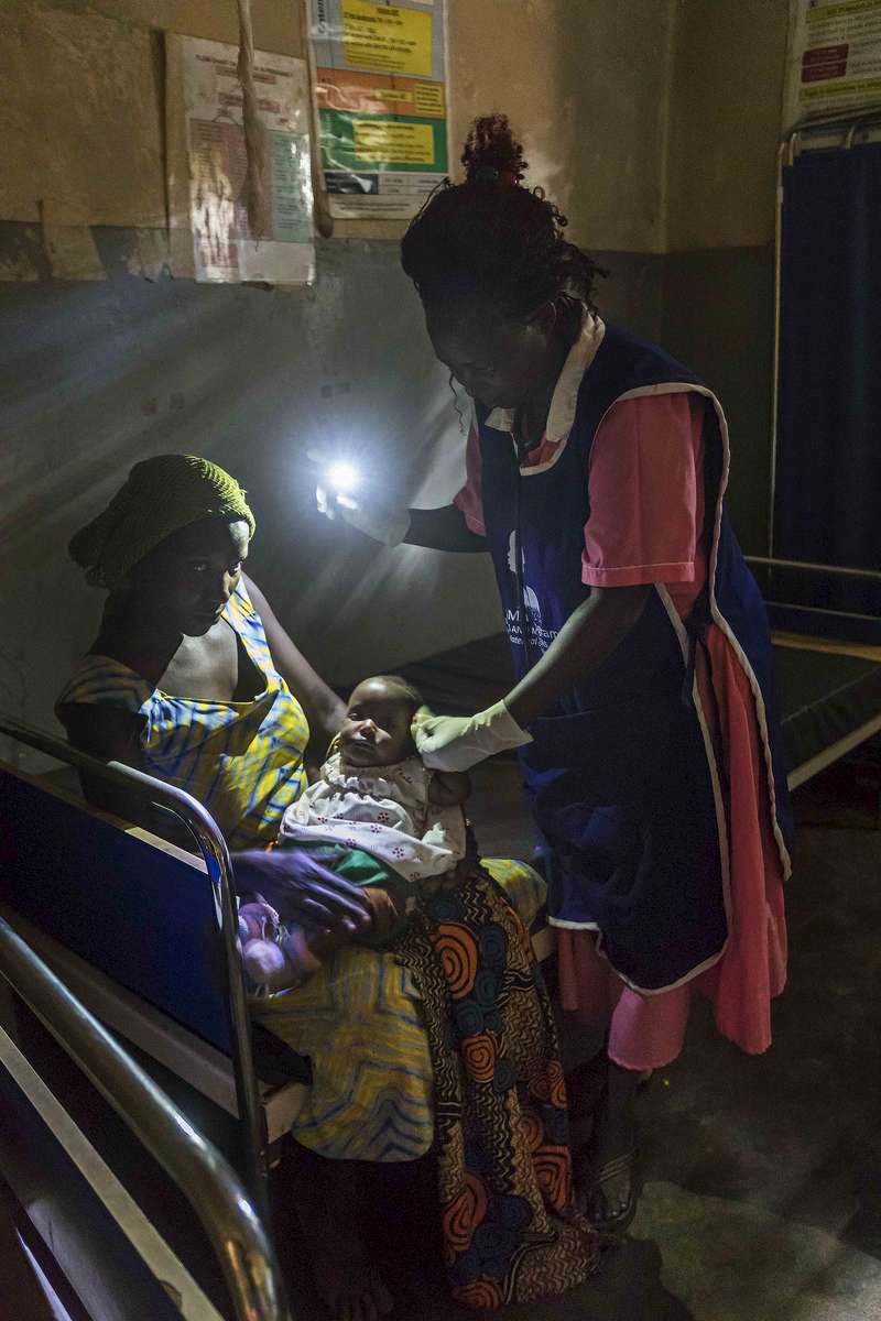 Patient exam by cell phone light, Rural Uganda