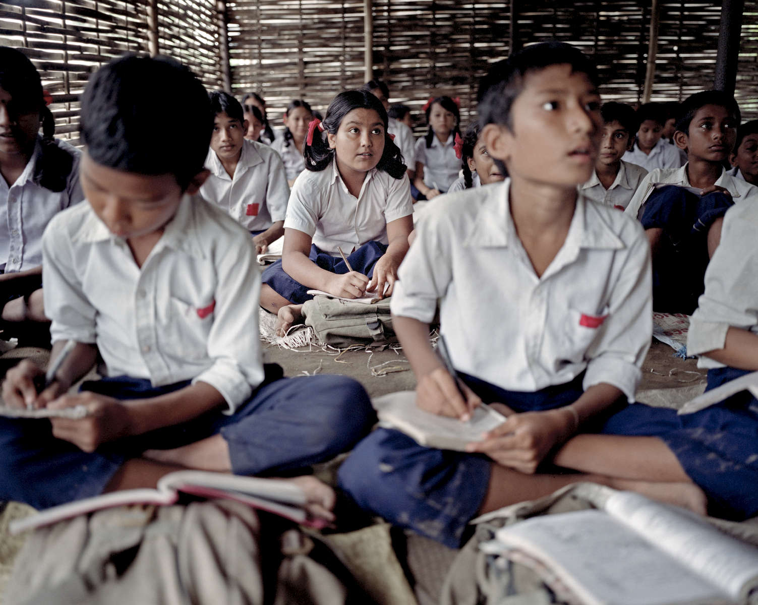 Bidhya en classe dans le camp de Beldangi. Les enfants ont accès à l’éducation grâce au Haut Commissariat pour les Réfugiés (HCR) et l’organisation non-gouvernementale Caritas. Ils apprennent les sciences, la géographie, l’histoire, le Népalais et le Dzongkha la langue Bhoutanaise. Népal, 2009.