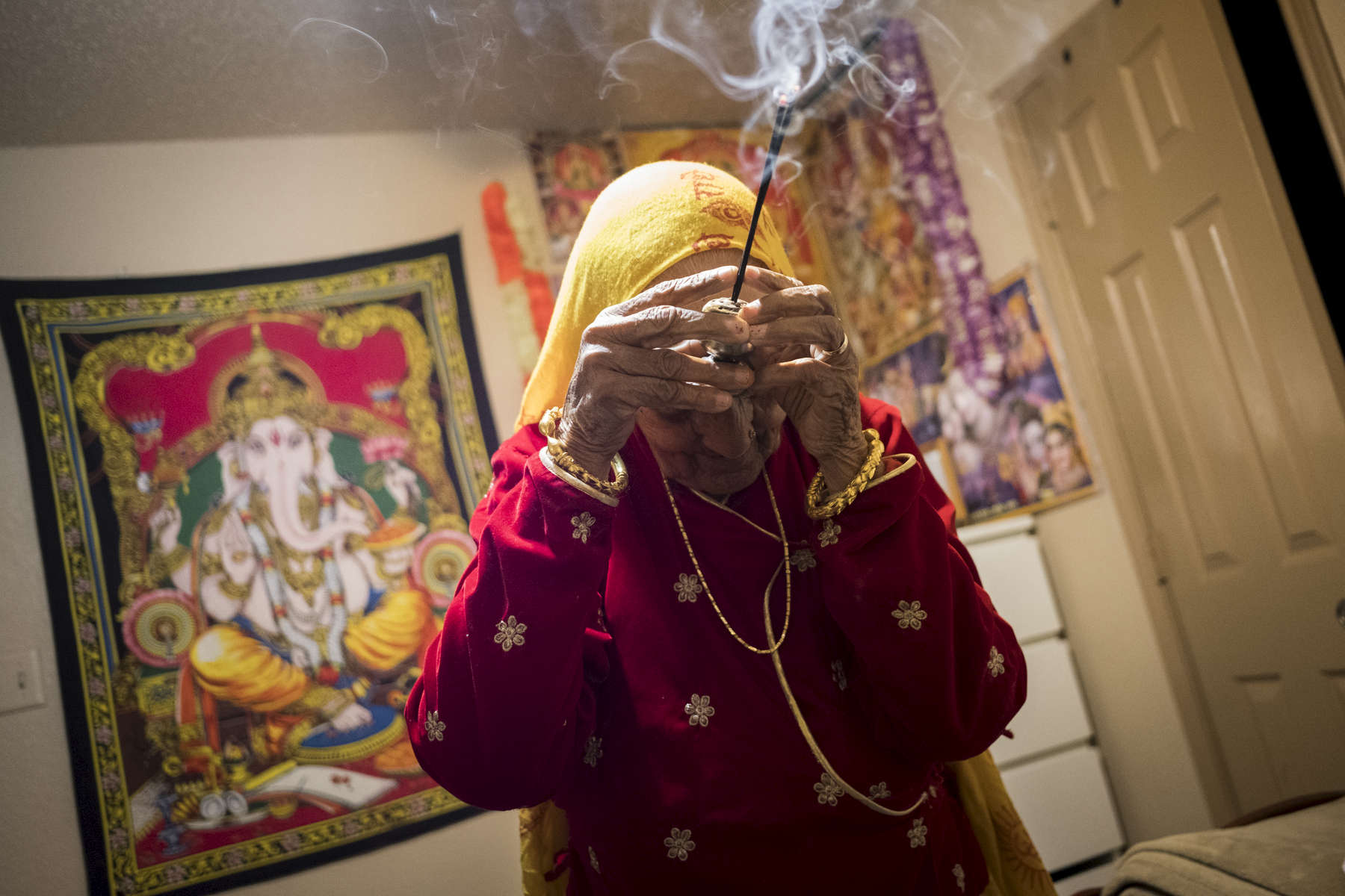 Radika priant dans sa chambre devant un autel représentant des divinités hindous. Les Lothsampas sont de confession Hindou. La communauté de Dallas a émi le souhait de lever des fonds pour la construction d'un temple, mais le projet reste encore en suspens. Watauga, Etats-Unis, 2018.