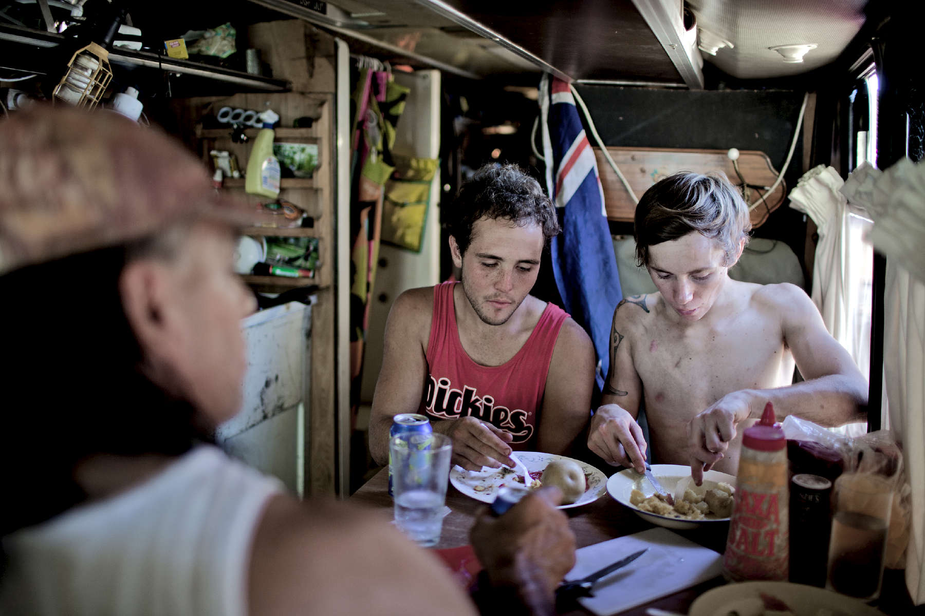 Michael, son fils Marshall et Hayden un jeune boxeur déjeunent dans le bus. Afin de pouvoir voyager facilement Michael a équipé son bus comme un petit appartement avec une cuisine, une douche et un lit. Katherine, TN, Australie, Juillet 2013.
