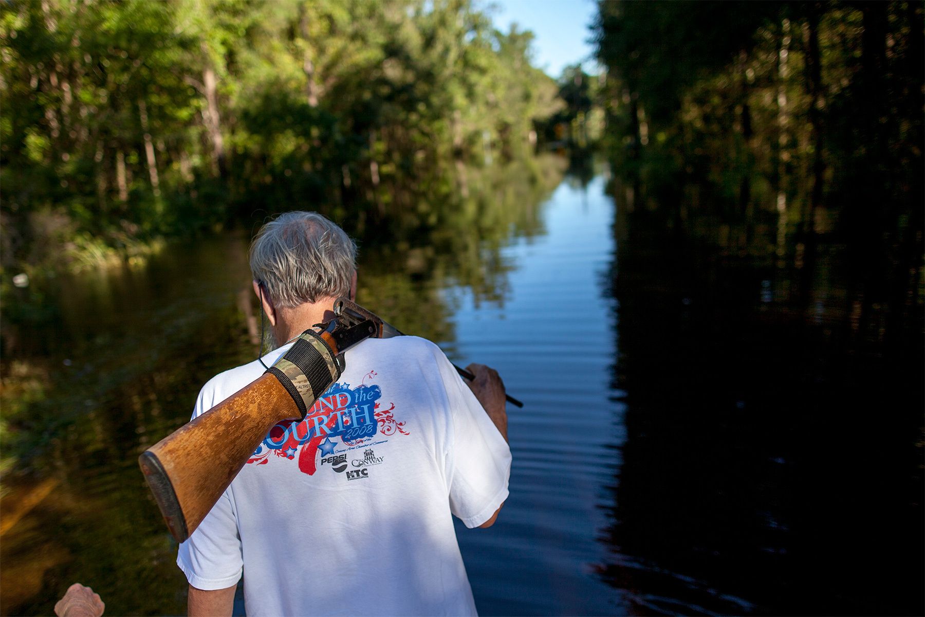 Harry Lockwood of River Road carries a rifle for snakes as he and his wife Kaye (Not Pictured) walk along flooded Lee's Landing Circle in Conway, South Carolina October 7, 2015. Rescuers searched early Wednesday for two people missing in floodwaters in South Carolina, while authorities urged residents in hundreds of homes to seek higher ground. REUTERS/Randall Hill