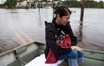 Miki Woodward holds family dog Butch while sitting on a johnboat along Waccamaw Drive in Conway, South Carolina October 6, 2015. The Woodward family came to the landing from their flooded neighborhood to meet daughter Kelly who had been separated from them for a few days because of the floods. Floodwaters from unprecedented rainfall in South Carolina have killed 11 people, closed some 550 roads and bridges and prompted hundreds of rescues of people trapped in homes and cars, officials said on Monday. REUTERS/Randall Hill