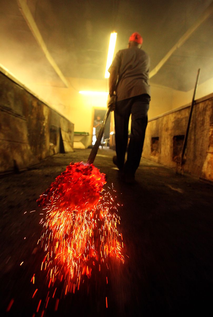 BBQ cooker Terry Blow carries red hot coals into the pit house at Scott's BBQ in Hemingway, South Carolina, June 20, 2012. The workers cooked 9 hogs in a process that took about 12 hours. The Southern Foodways Alliance and the University of Mississippi’s Center for the Study of Southern Culture made a stop at Scott's BBQ to complete the month-long trip to gather and preserve the stories behind South Carolina’s barbecue culture during their ongoing documentary project, The Southern BBQ Trail. According to food historian Rien Fertel and photographer Denny Culbert, who are conducting the study, there are only ten or 15 BBQ pits in the whole South that use the old-timey methods of fire coal pit cooked BBQ they use at Scott's.  REUTERS/Randall Hill  (UNITED STATES)