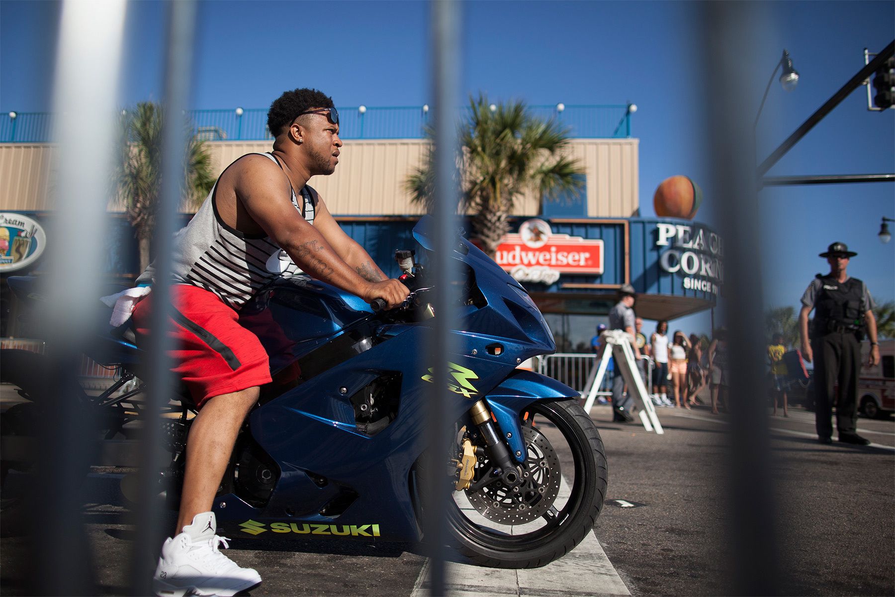 A biker is seen through the metal fencing blocking both sides of Ocean Boulevard during the 2015 Atlantic Beach Memorial Day BikeFest in Myrtle Beach, South Carolina May 24, 2015. After three people were killed and seven wounded in shootings during 2014 Bikefest, State officials called for an end to the event that draws thousands to the family-friendly beach town. Their efforts were unsuccessful. Bikers returned to Myrtle Beach - just a week after a bloody motorcycle gang shootout in Waco, Texas. But this time authorities are more prepared, with dozens of new surveillance cameras and a police force three times the size of last year's. REUTERS/Randall Hill